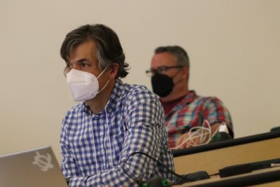 Roger Travis (blue and white checkered shirt) and Mark Pearsall (red, white, and green plaid patterned shirt with black glasses) watch a presentation in an ITE classroom